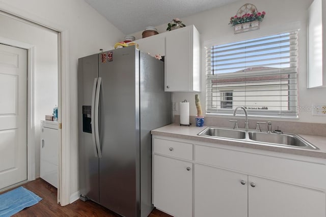 kitchen with light countertops, white cabinetry, stainless steel fridge, and a sink