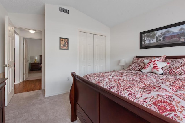 bedroom featuring lofted ceiling, a closet, baseboards, visible vents, and light carpet