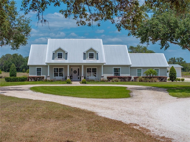 cape cod house featuring covered porch, curved driveway, metal roof, and a front yard