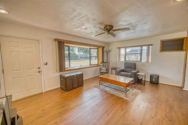 living area featuring plenty of natural light, light wood-style flooring, baseboards, and ceiling fan