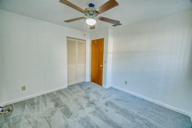 unfurnished bedroom with a closet, carpet, visible vents, ceiling fan, and baseboards