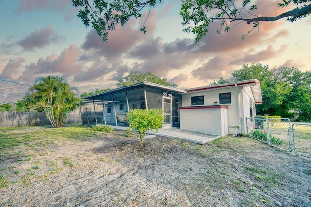 view of front of property featuring a sunroom, a gate, and a fenced backyard
