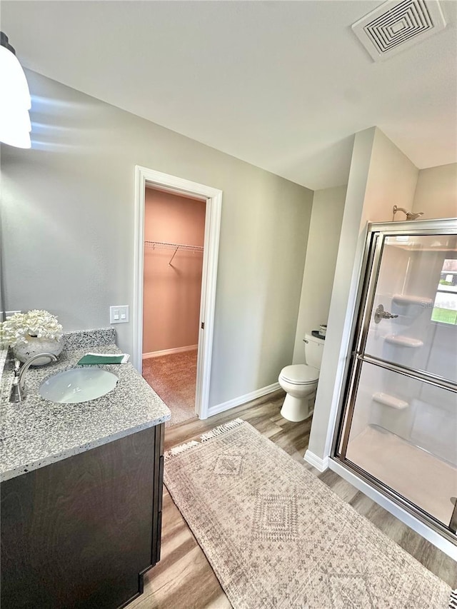 4007 Loretto Ave, Sebring, FL 33872 - bathroom with wood finished floors, a stall shower, toilet, vanity, and a walk in closet