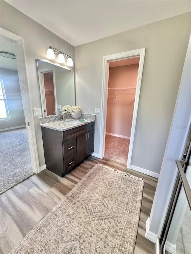 4007 Loretto Ave, Sebring, FL 33872 - full bath with vanity, a walk in closet, wood finished floors, and baseboards