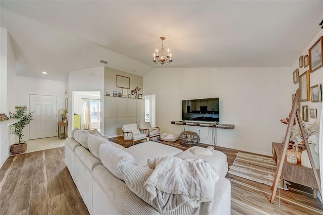 living room featuring visible vents, wood finished floors, lofted ceiling, and a notable chandelier