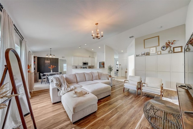 living area with a notable chandelier, recessed lighting, light wood finished floors, visible vents, and vaulted ceiling