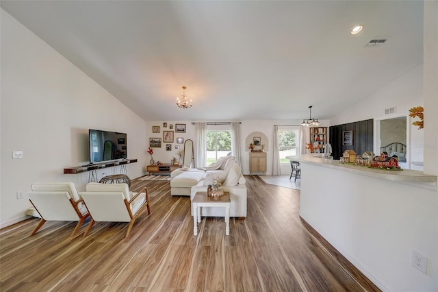 living area featuring an inviting chandelier, visible vents, and lofted ceiling