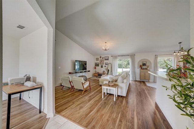 living room featuring vaulted ceiling, a chandelier, light wood-style flooring, and visible vents