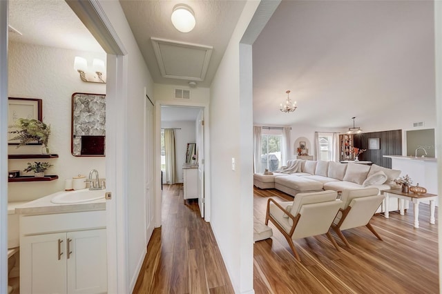 living area with a chandelier, visible vents, and wood finished floors