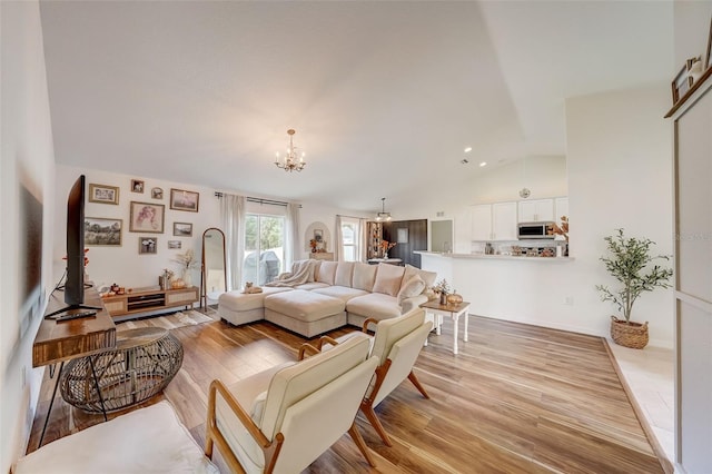 living area featuring light wood finished floors, lofted ceiling, and a notable chandelier