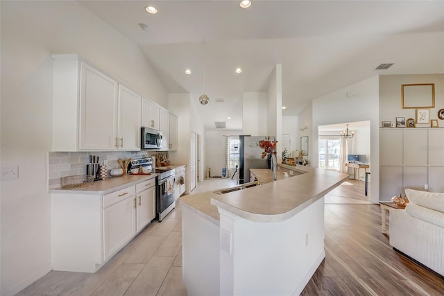 kitchen with backsplash, light countertops, white cabinets, and appliances with stainless steel finishes