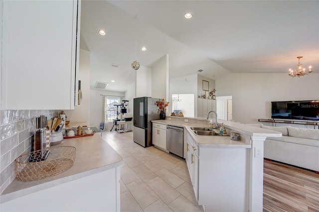 kitchen featuring stainless steel appliances, a sink, open floor plan, vaulted ceiling, and light countertops