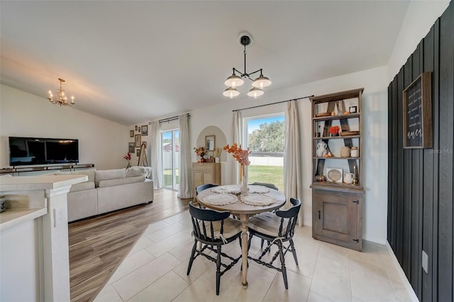 dining area with lofted ceiling, a notable chandelier, and light tile patterned floors