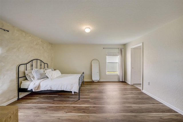 bedroom with baseboards and wood finished floors