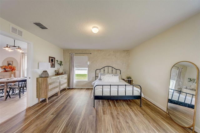 bedroom with baseboards, visible vents, and wood finished floors