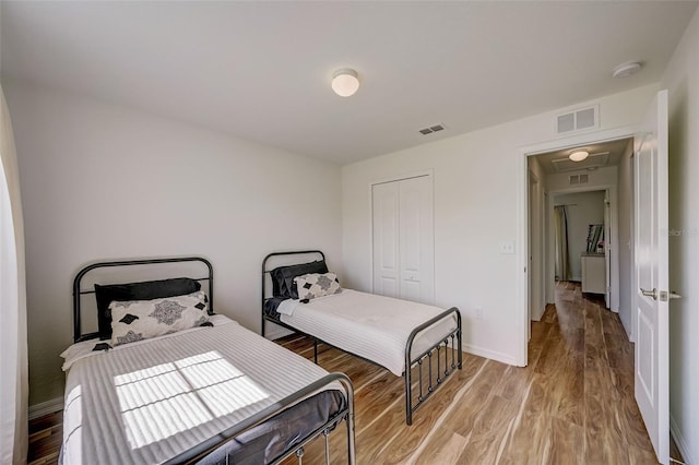 bedroom featuring a closet, light wood-type flooring, visible vents, and baseboards