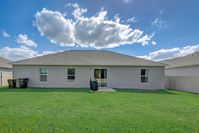 back of house featuring stucco siding, fence, and a lawn