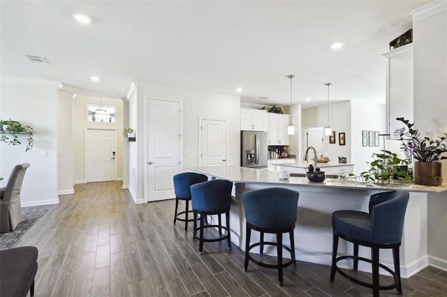 kitchen featuring visible vents, a breakfast bar area, stainless steel refrigerator with ice dispenser, white cabinets, and dark wood finished floors
