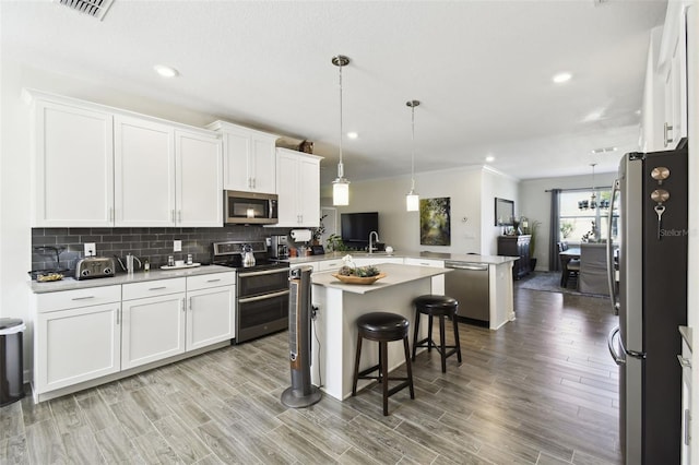 kitchen featuring a kitchen island, stainless steel appliances, white cabinets, and a peninsula