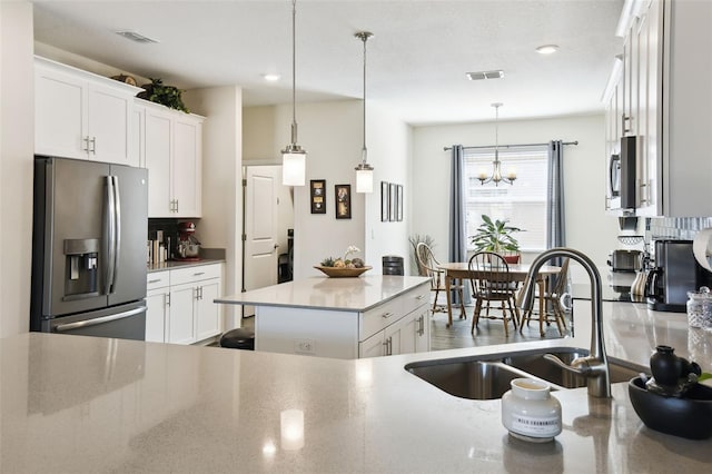 kitchen with a sink, appliances with stainless steel finishes, white cabinets, and backsplash