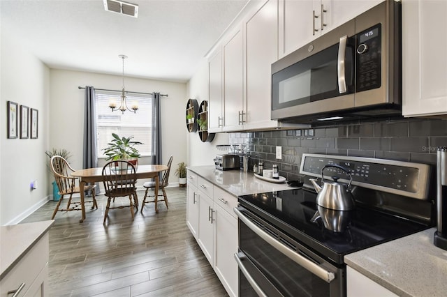 kitchen featuring appliances with stainless steel finishes, a chandelier, baseboards, backsplash, and visible vents