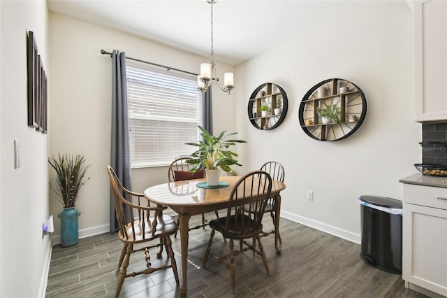 dining area with baseboards, a notable chandelier, and dark wood-style floors