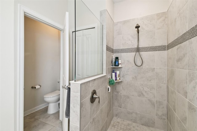 full bathroom featuring tile patterned flooring, baseboards, toilet, and tiled shower