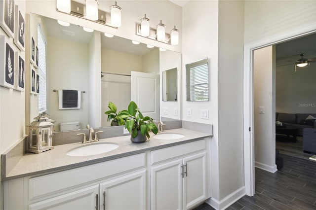 full bathroom with a sink, toilet, double vanity, and wood finished floors