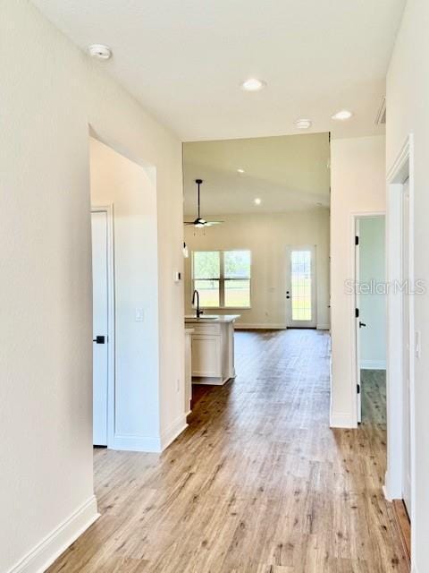 interior space with baseboards, a ceiling fan, and light wood-type flooring