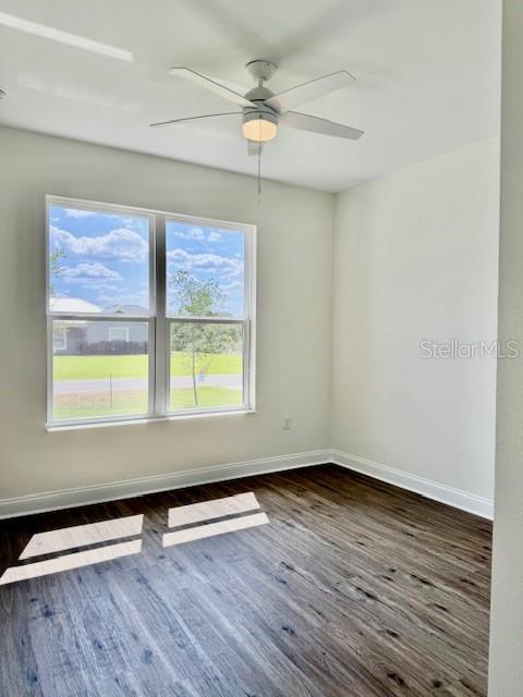 spare room featuring dark wood-type flooring, baseboards, and ceiling fan