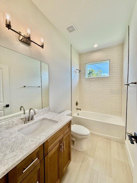 bathroom featuring tub / shower combination, vanity, toilet, and visible vents