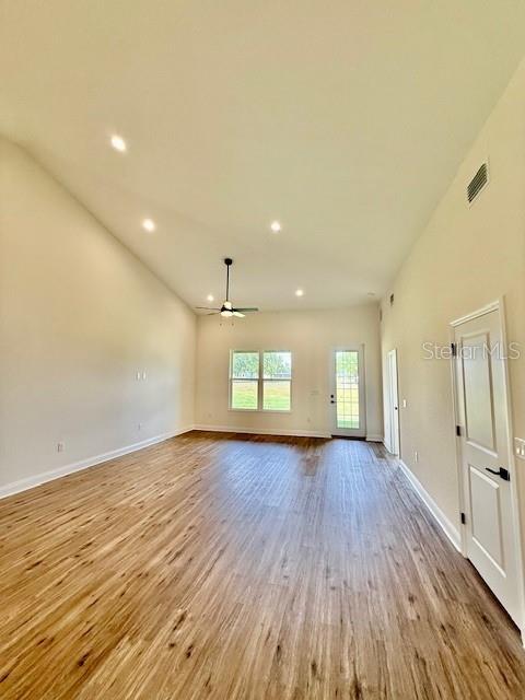 unfurnished living room with baseboards, ceiling fan, visible vents, and wood finished floors
