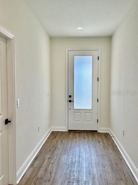 doorway with baseboards and wood finished floors