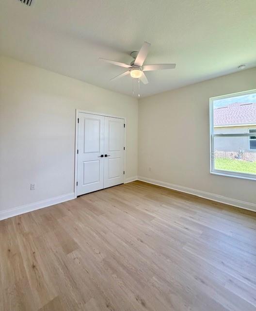 5275 Pebble Beach Dr, Sebring, FL 33872 - unfurnished bedroom featuring baseboards, ceiling fan, wood finished floors, and a closet