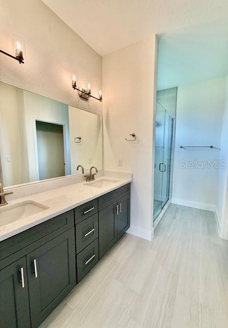 5275 Pebble Beach Dr, Sebring, FL 33872 - full bath with double vanity, a sink, baseboards, and a stall shower