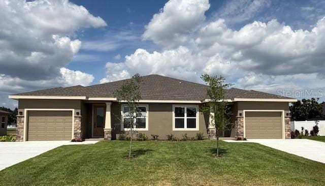 ranch-style house featuring a front yard, a garage, concrete driveway, stone siding, and stucco siding