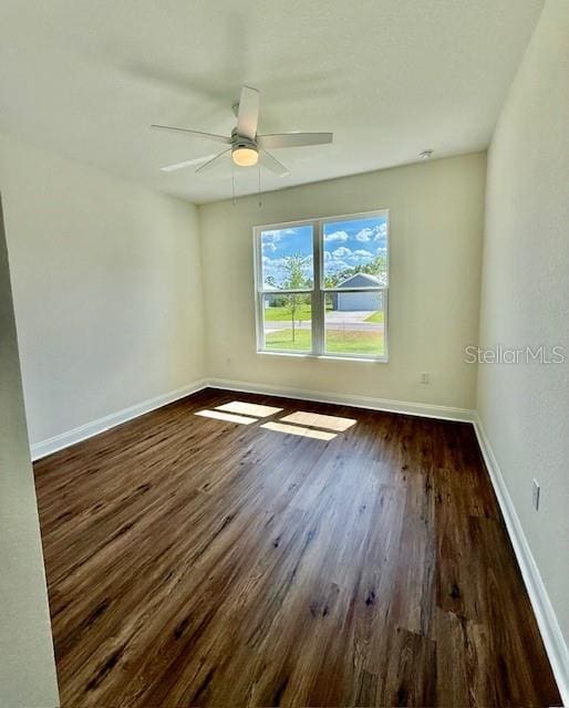 unfurnished room featuring baseboards, a ceiling fan, and dark wood-type flooring