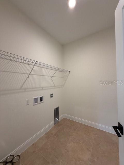 washroom featuring laundry area, baseboards, tile patterned flooring, and hookup for a washing machine