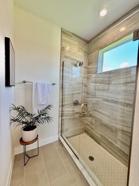 bathroom with baseboards, tile patterned flooring, and a stall shower