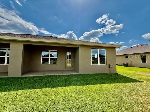 back of property featuring a patio, stucco siding, a yard, and cooling unit