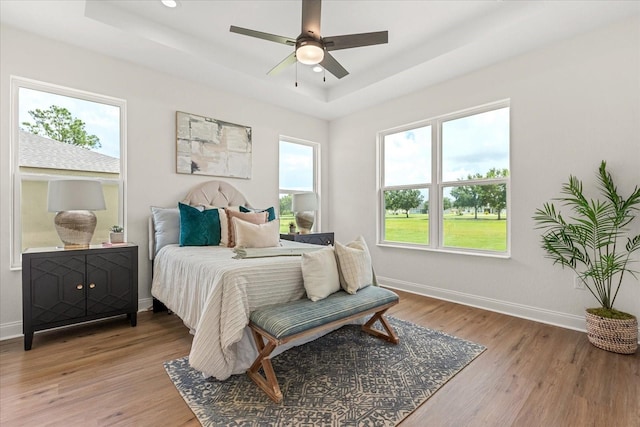 5277 Pebble Beach Dr, Sebring, FL 33872 - bedroom featuring a raised ceiling, light wood-style flooring, and a ceiling fan