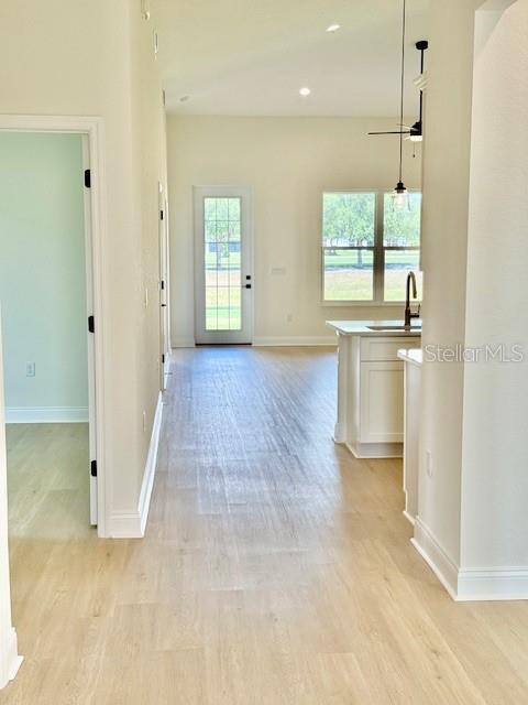 5273 Pebble Beach Dr, Sebring, FL 33872 - hall featuring baseboards, a sink, light wood-style flooring, and recessed lighting