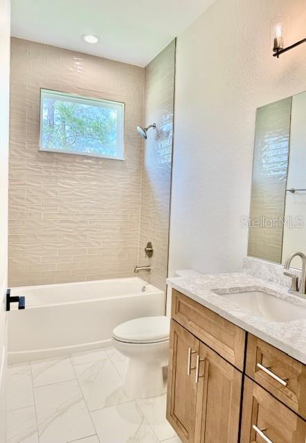 5273 Pebble Beach Dr, Sebring, FL 33872 - bathroom featuring bathing tub / shower combination, vanity, toilet, and marble finish floor