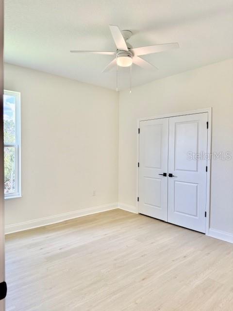 5273 Pebble Beach Dr, Sebring, FL 33872 - unfurnished bedroom featuring baseboards, ceiling fan, light wood finished floors, and a closet