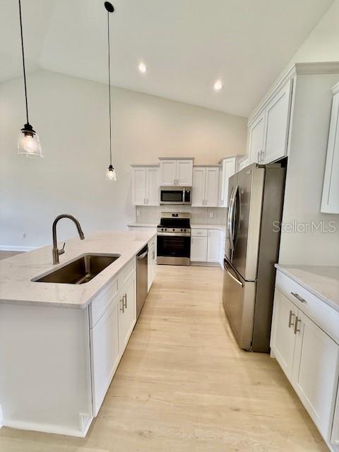 5273 Pebble Beach Dr, Sebring, FL 33872 - kitchen with a sink, light wood finished floors, a kitchen island with sink, stainless steel appliances, and pendant lighting