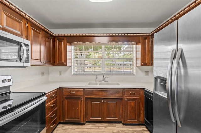 kitchen featuring light wood finished floors, light countertops, stainless steel appliances, and a sink