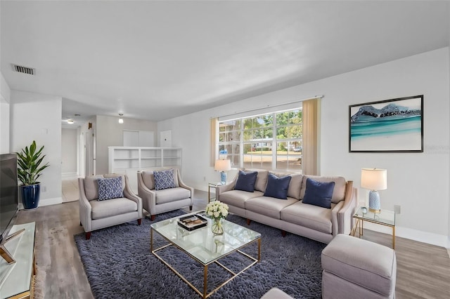 living area featuring baseboards, visible vents, and wood finished floors