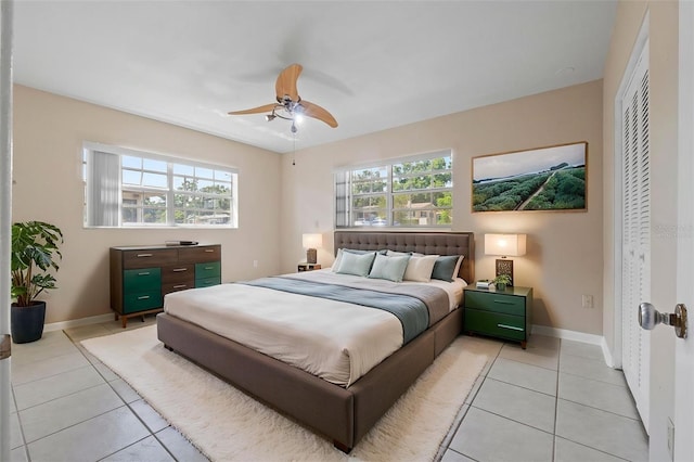 bedroom with ceiling fan, baseboards, and light tile patterned floors