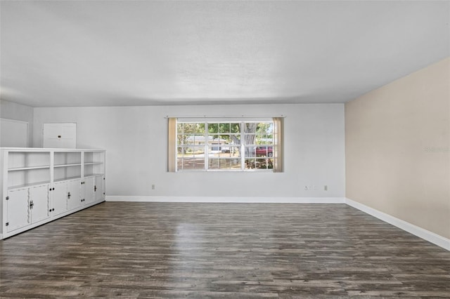 unfurnished room with baseboards and dark wood finished floors