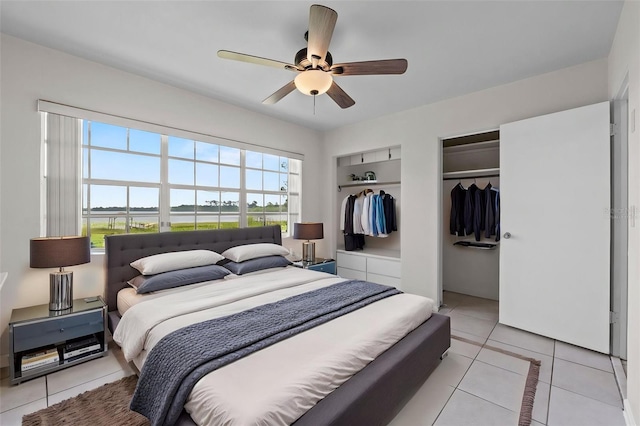 bedroom with light tile patterned floors, two closets, and a ceiling fan